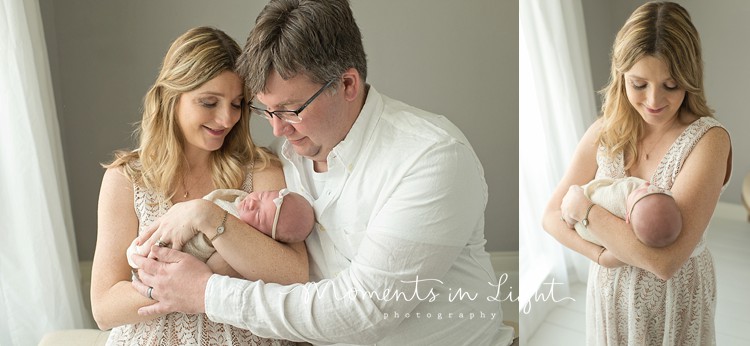 newborn with parents in soft colors by window