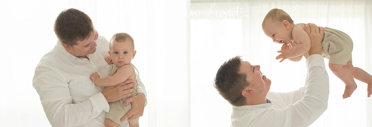 dad holding baby boy next to window light in Houston photo studio