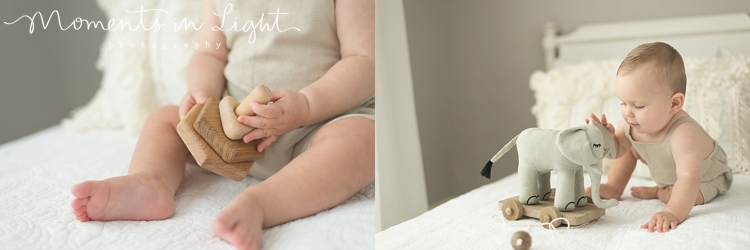 baby boy wearing cream romper playing with toys on white bed in Houston photo studio