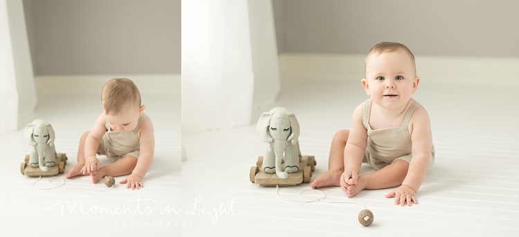 baby boy wearing linen romper playing with toy elephant in Houston photo studio
